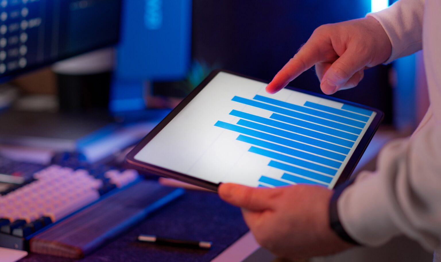 Profissional analisando gráfico de barras em tablet, representando o painel mensal de métricas de automação de marketing. Foto de Jakub Zerdzicki via Pexels.