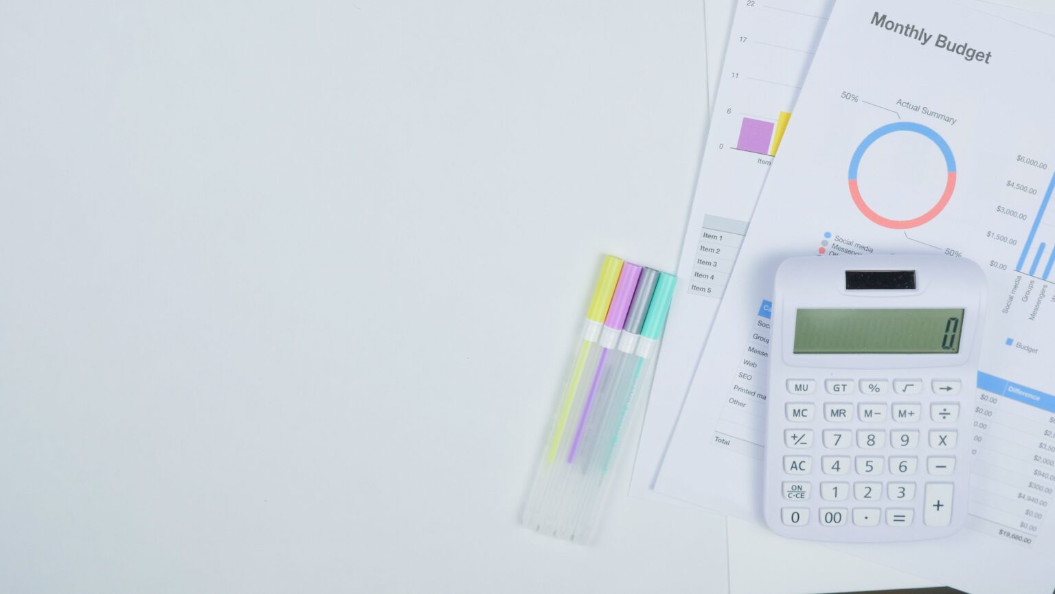 Mesa de trabalho com calculadora, documentos de planejamento de orçamento e canetas coloridas. Foto de Kindel Media via Pexels.