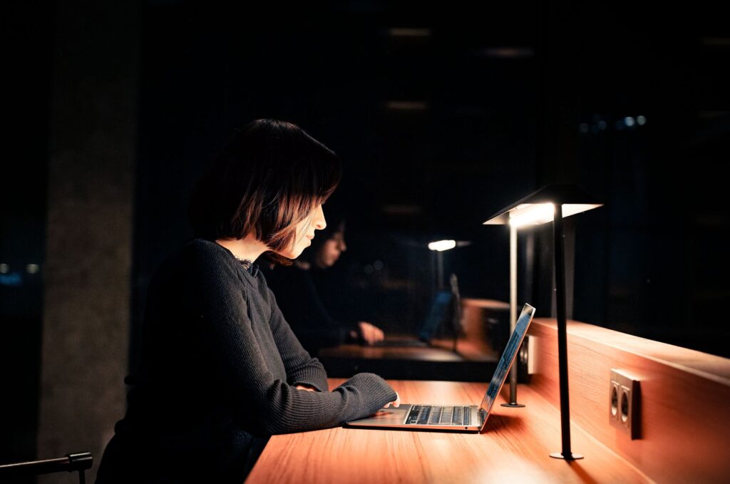 Mulher trabalhando no laptop à noite, abrindo um pedido fora do horário comercial. Foto de Oktay Köseoğlu via Pexels.
